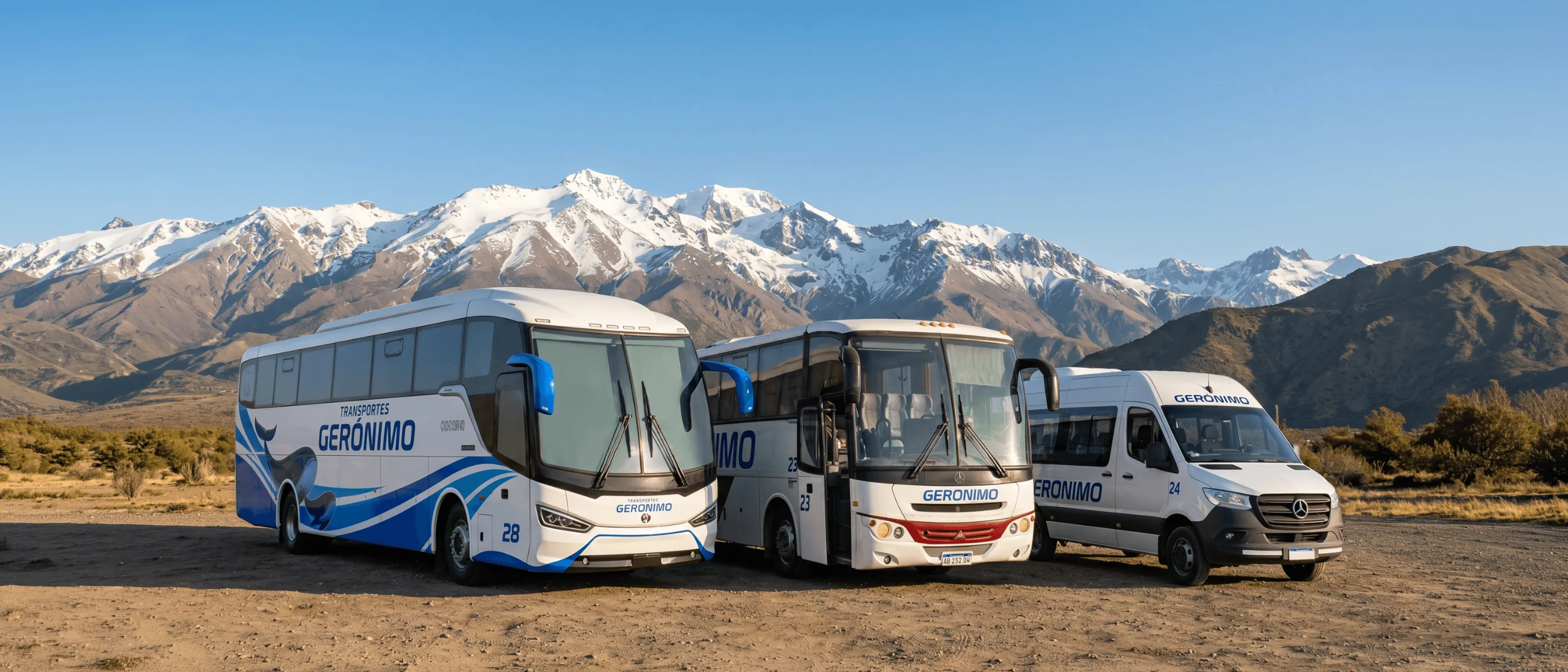 A white tour bus with the name "GERONIMO" travels along a scenic mountain road under a clear blue sky.